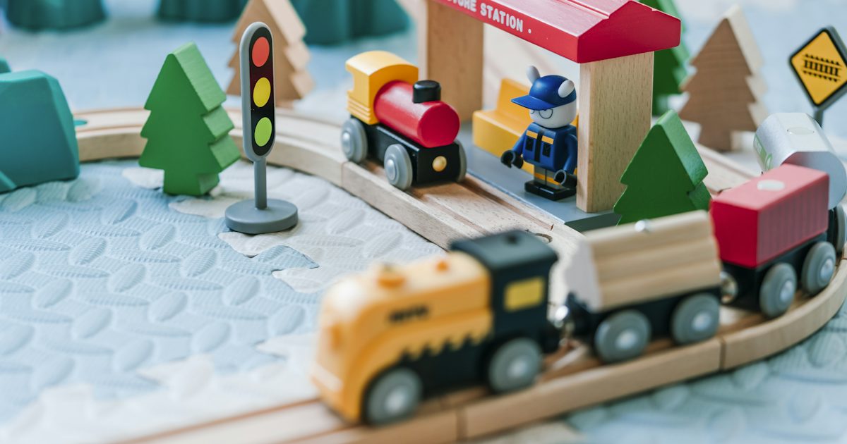 Circuit de train en bois avec locomotives, sapins et petite gare, jouets typiques des achats de fin d'année
