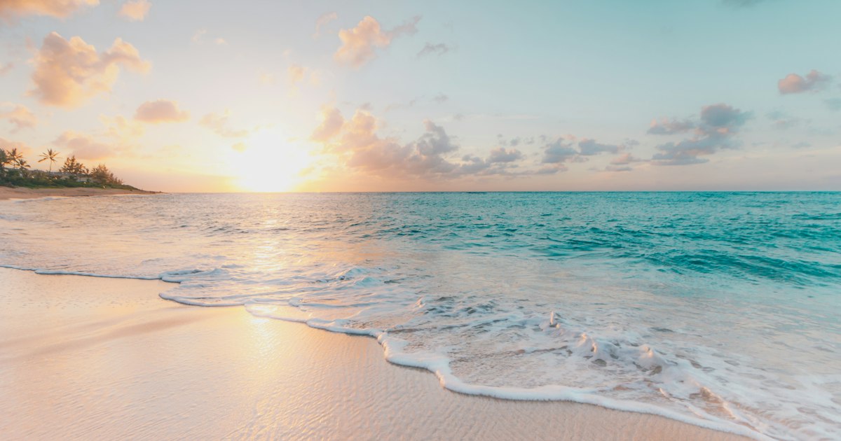 Plage au coucher du soleil, symbole des séjours et vacances financés par l'aide aux vacances des Caf