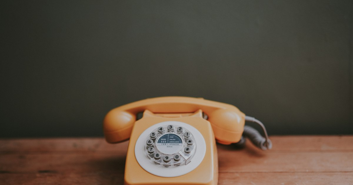 Téléphone fixe à cadran posé sur une table en bois